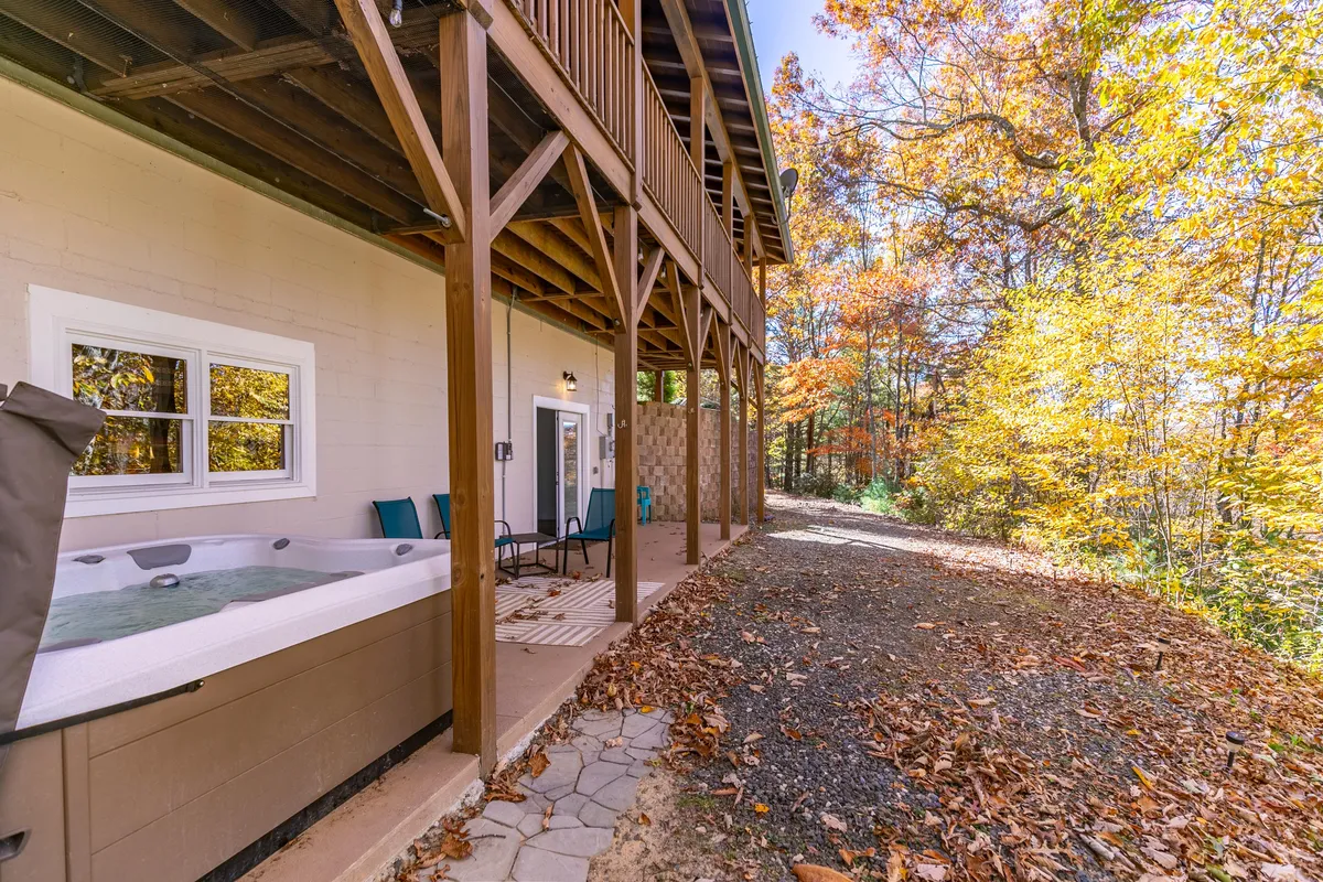 This image features a bubbling hot tub nestled on a wraparound deck, framed by lush foliage and tranquil forest views. The deck provides ample space for relaxation and gathering, with the surrounding trees creating a private, serene atmosphere.